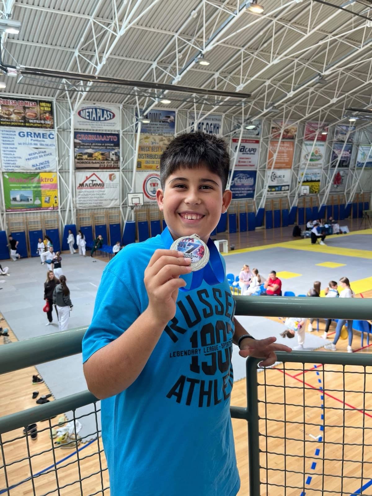 Young athlete on a balcony above the competition floor holding a silver medal